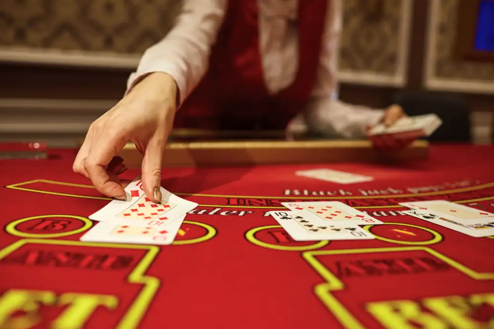 Nahaufnahme eines Live-Dealers im Casino, der Karten am Blackjack-Tisch verteilt, mit unauffälliger Raumbeduftung für optimale Spielerfahrung.