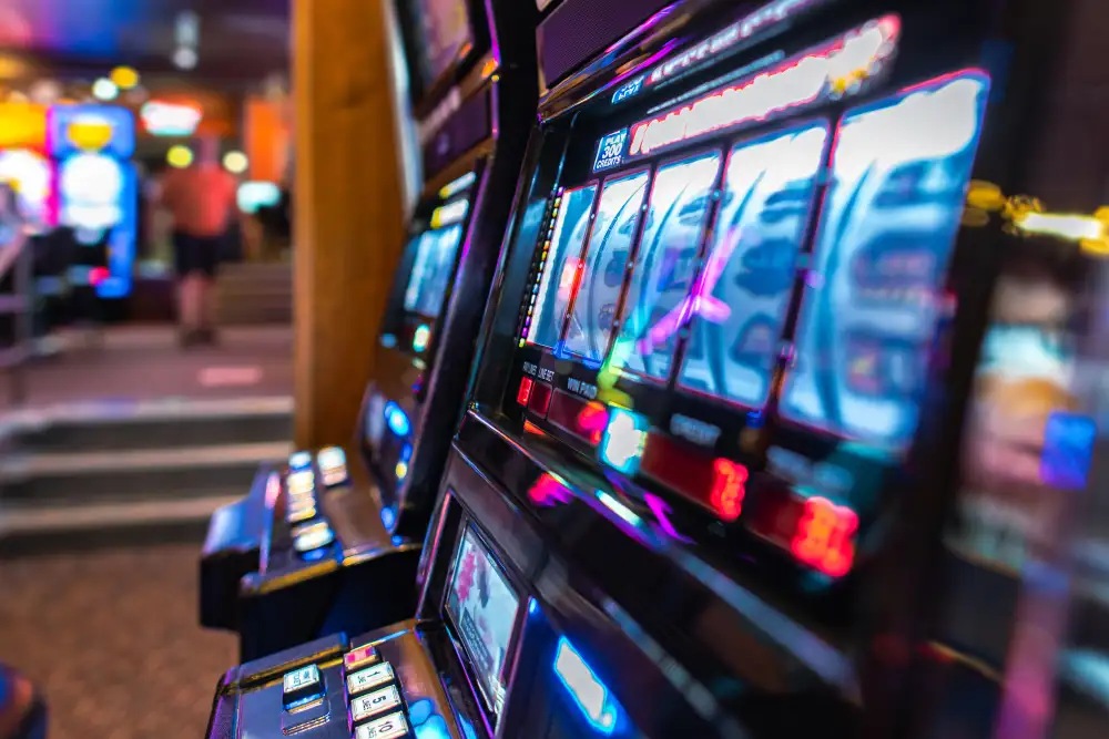 Reihe beleuchteter Spielautomaten in einer Casino Spielhalle, wo Duftmarketing die Konzentration und Verweildauer der Gäste fördert.